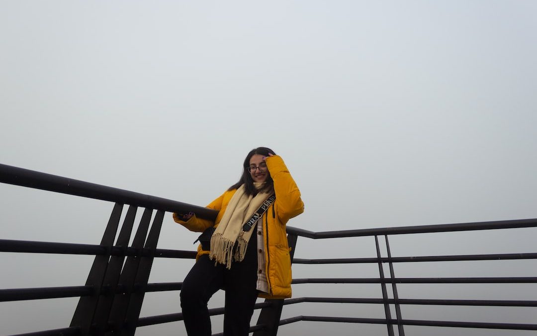 a woman in a yellow jacket standing on a railing