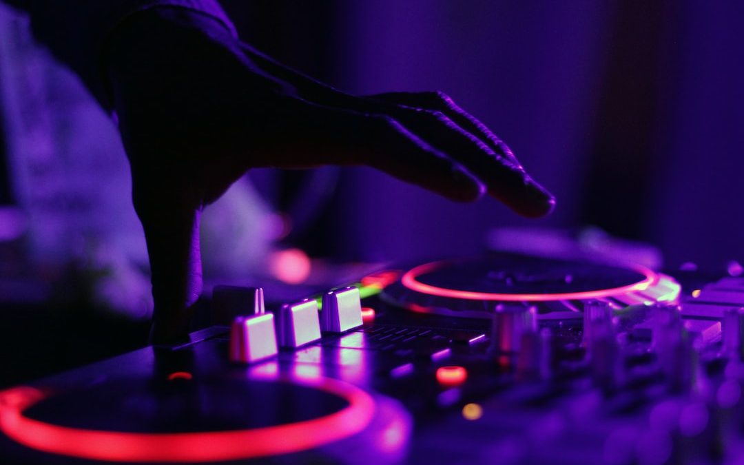 selective focus silhouette photography of man playing red-lighted DJ terminal