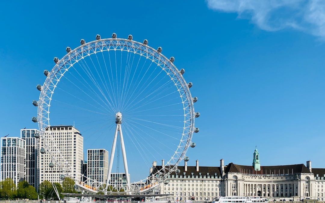 white ferris wheel near white concrete building under blue sky during daytime