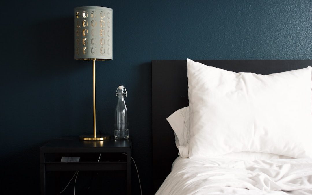 gray table lamp beside white bed pillow