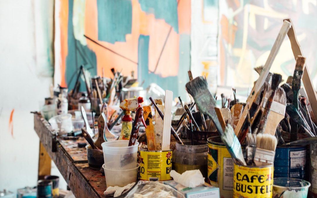 assorted-color paint brush on brown wooden table top