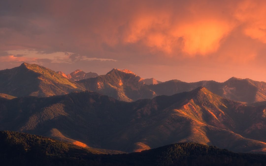 brown and black mountains under orange sky