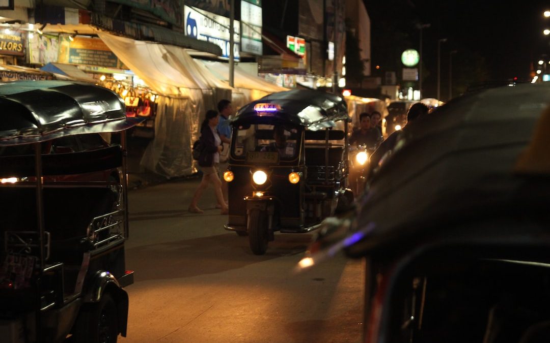 a group of people walking down a sidewalk next to a row of cars