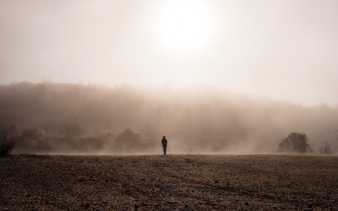 person standing on gray sand during foggy weather