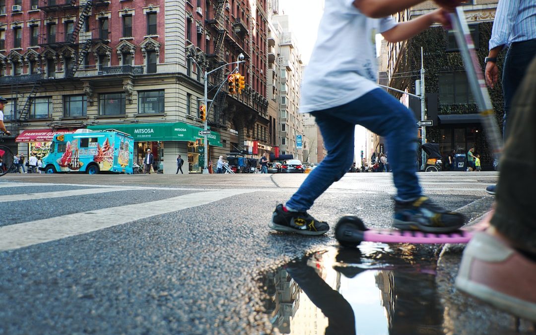 man in white t-shirt and blue denim jeans jumping on wet road during daytime