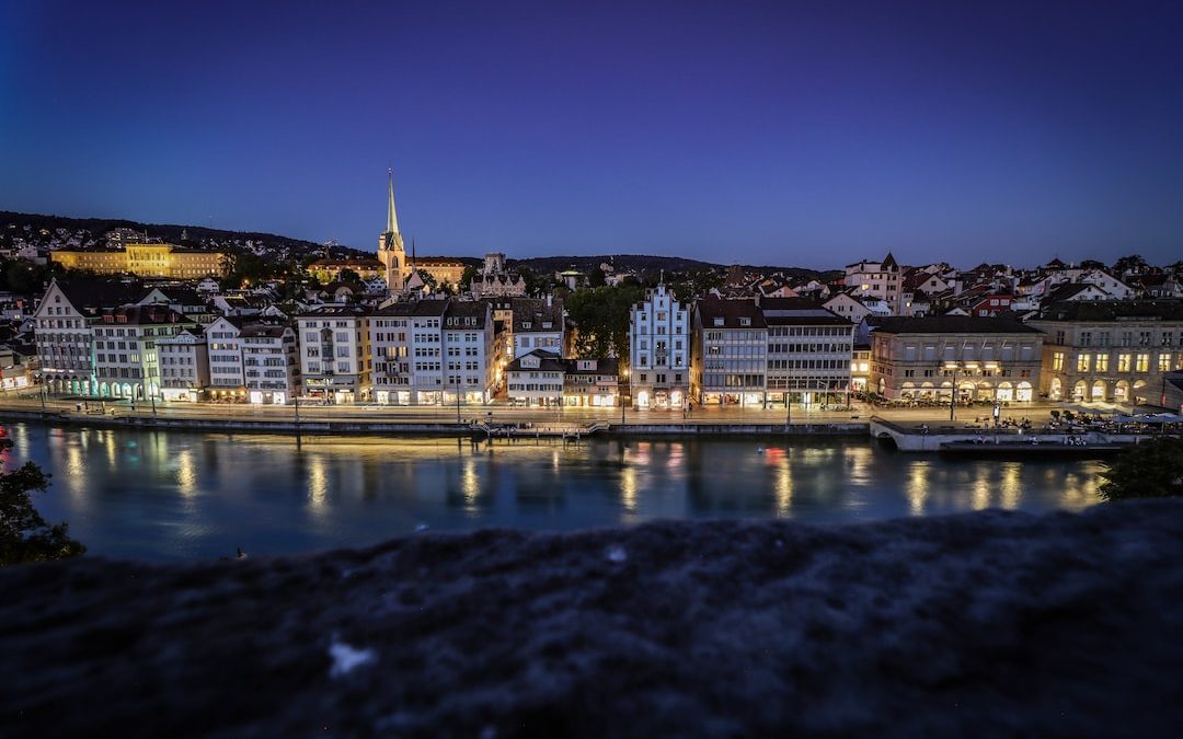 city buildings near body of water during night time