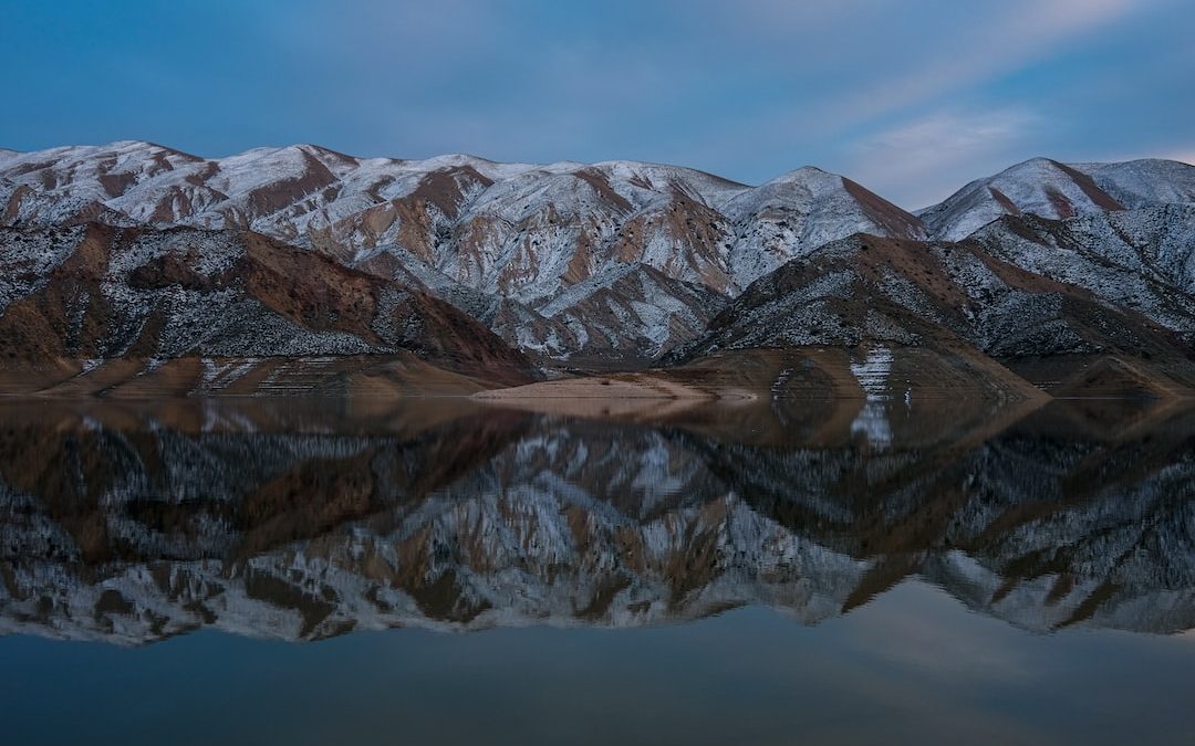 a mountain range is reflected in the still water of a lake