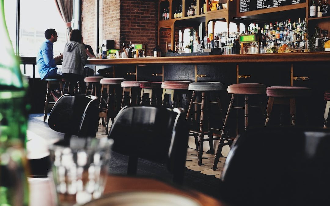 two person sitting on bar stool chair in front of bar front desk