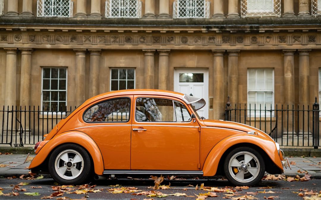 orange volkswagen beetle parked near building