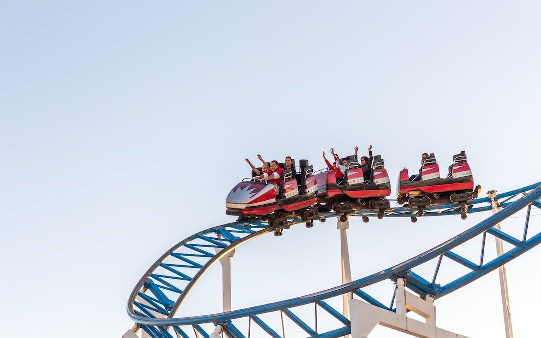 people riding red and white roller coaster during daytime