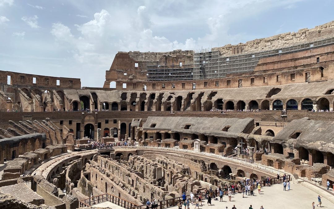 a large ancient building with many people with Colosseum in the background