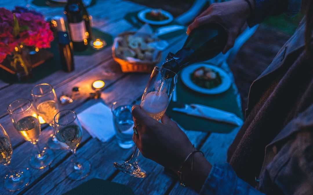 person putting wine on flute glass