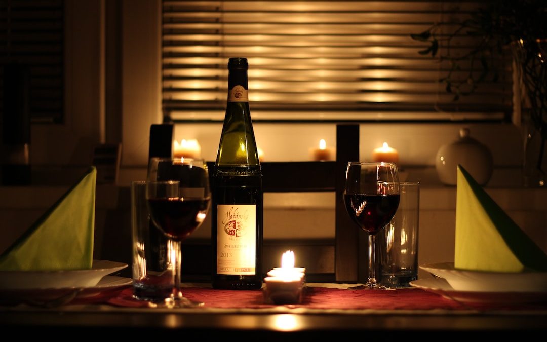 wine glass filled with wine beside bottle on table