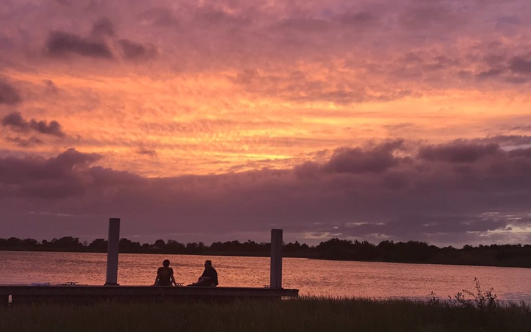 two people sitting near body of water