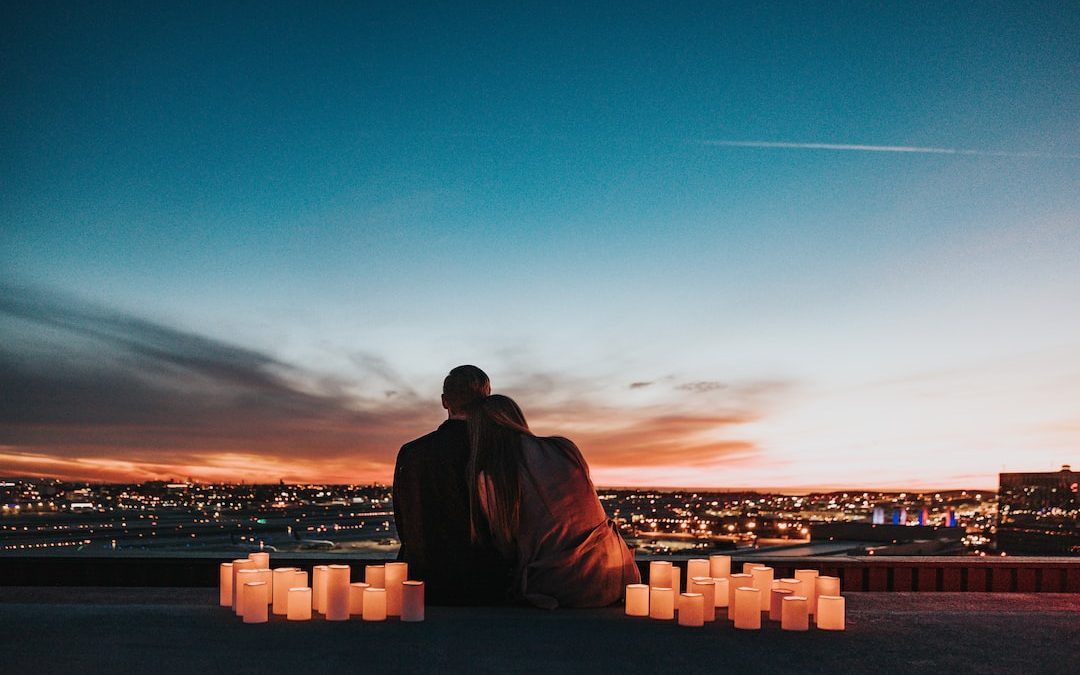 couple sitting on the field facing the city