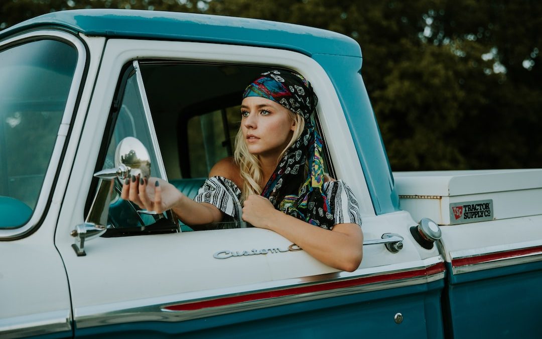 photography of woman holding side mirror in white and green 2-door pickup truck