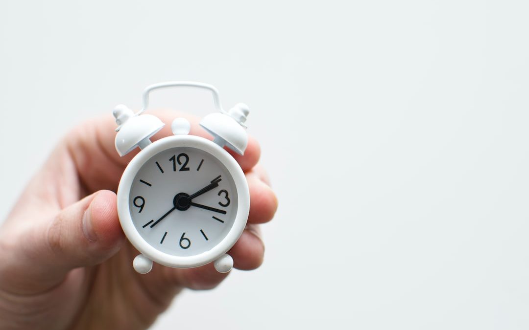 person holding white mini bell alarmclock