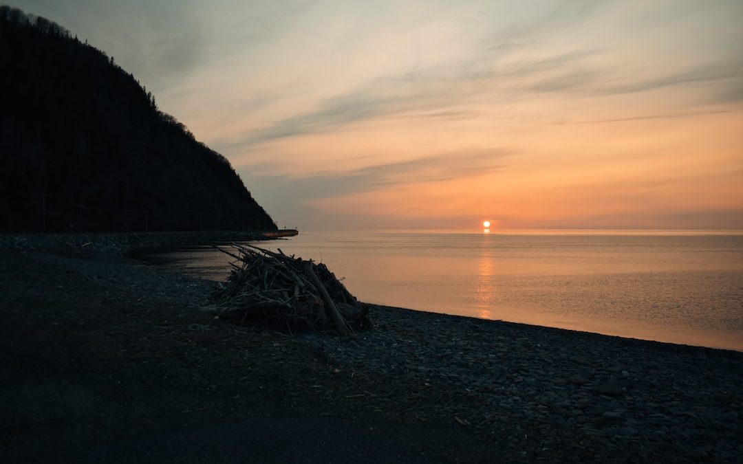 the sun is setting over the water at the beach