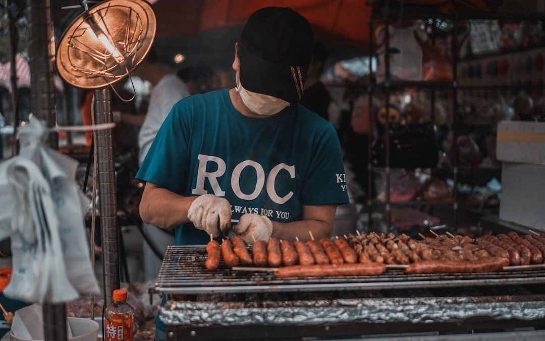 man in blue and white crew neck t-shirt standing in front of food stall