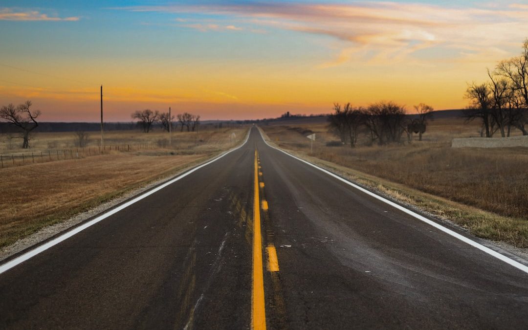 a long empty road in the middle of a field