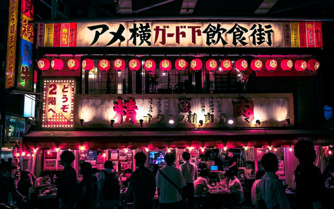 a group of people in front of a building with neon signs