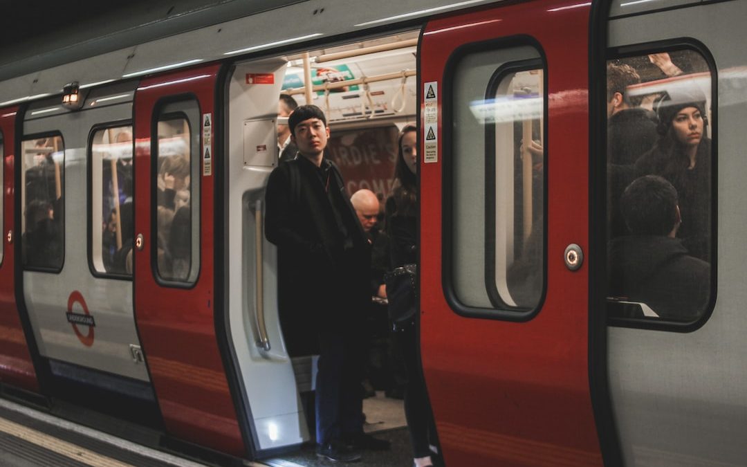 a man standing on a train platform next to a red and silver train