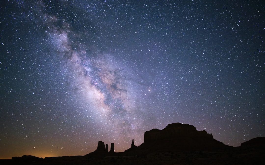 a starry night sky over a rocky mountain