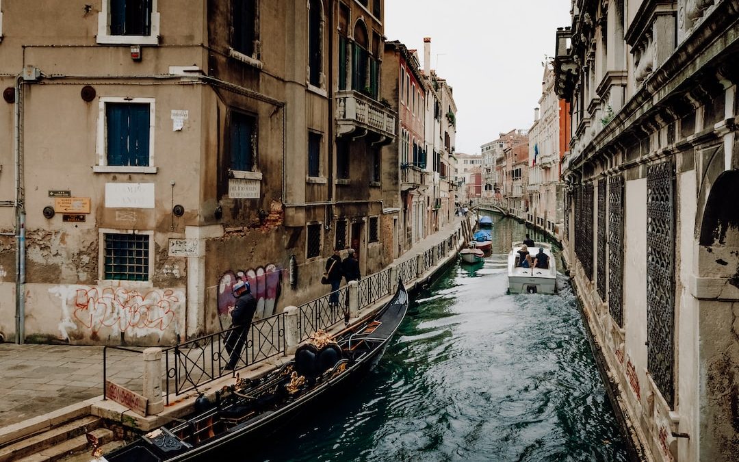 a boat traveling down a canal next to tall buildings