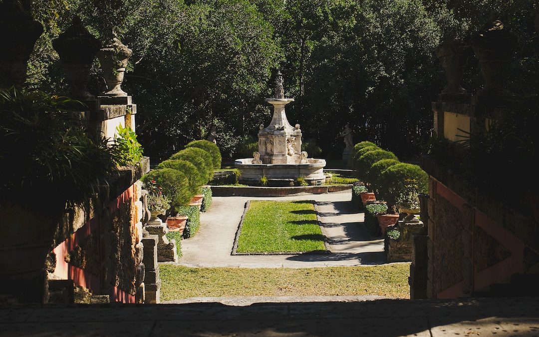 gray concrete fountain in the middle of green trees