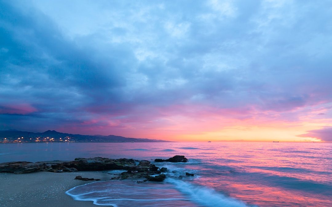 waves of body of water splashing on sand