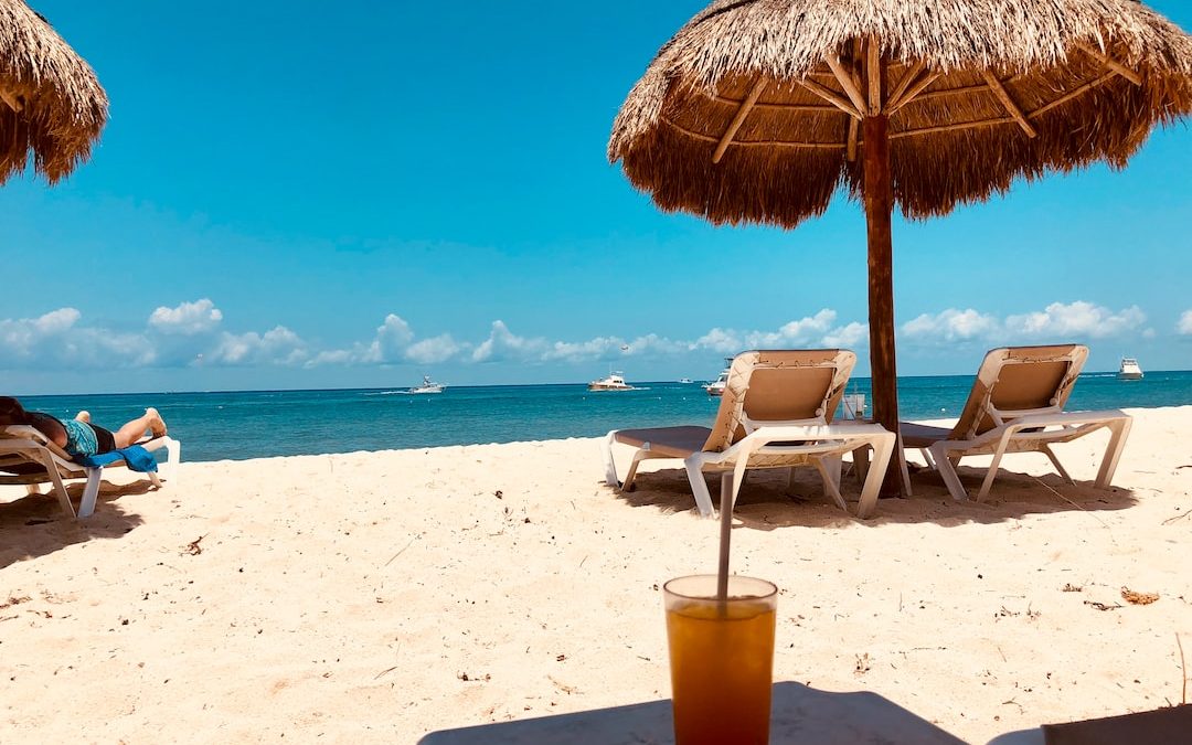 brown parasol and two beach chairs on beach sand