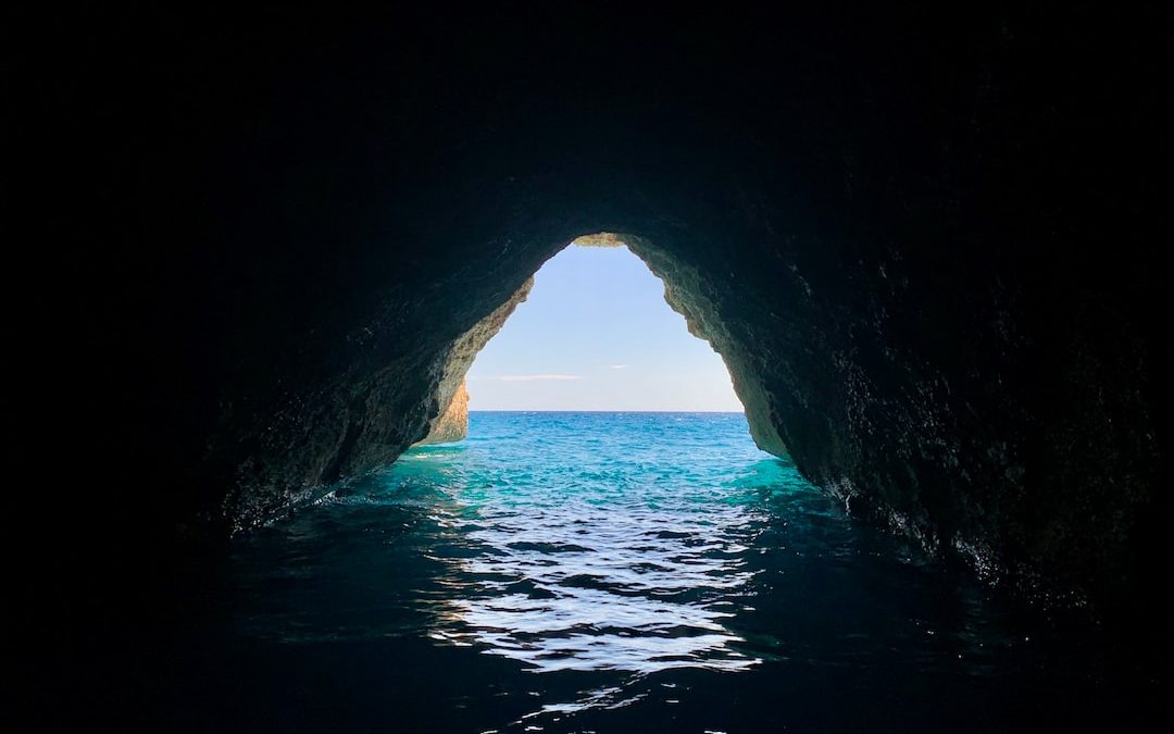 cave with body of water during daytime