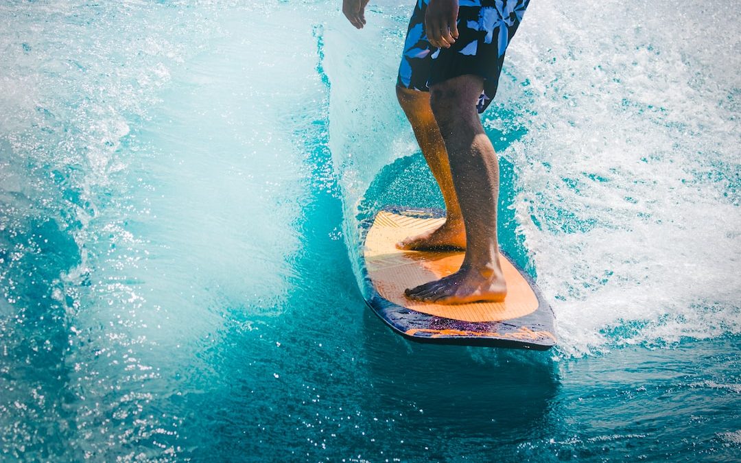 man riding wave with orange surfboard