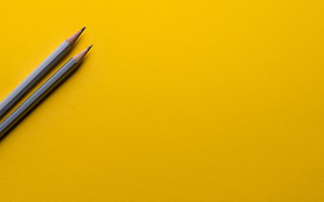 two gray pencils on yellow surface