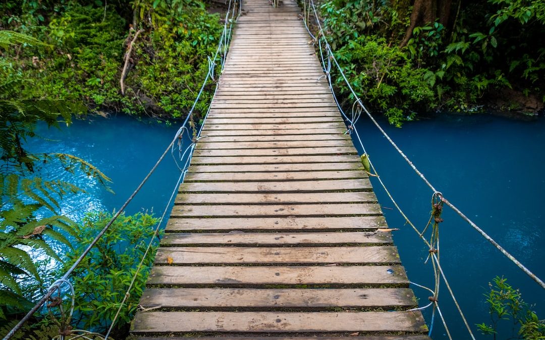 a wooden suspension bridge over a blue river
