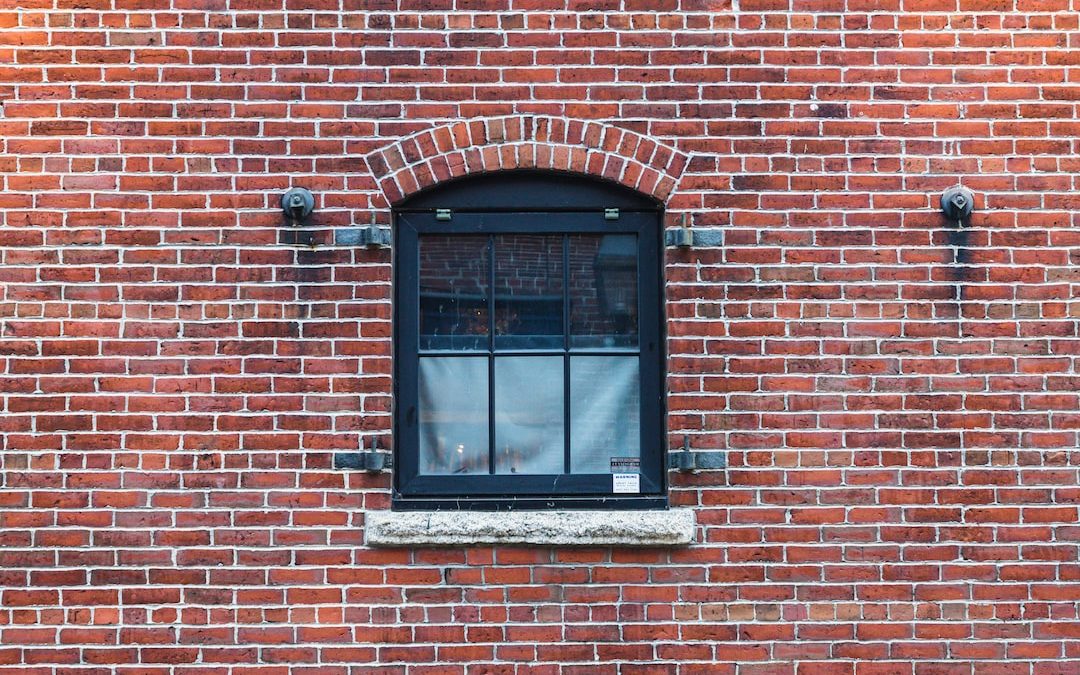 a brick wall with a window and a bench