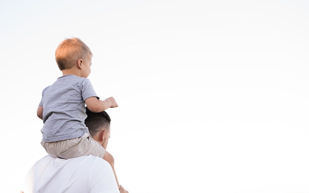 man in white shirt carrying boy