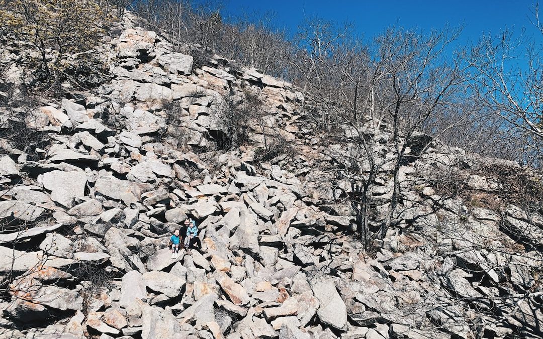 a couple of people climbing up a rocky hill