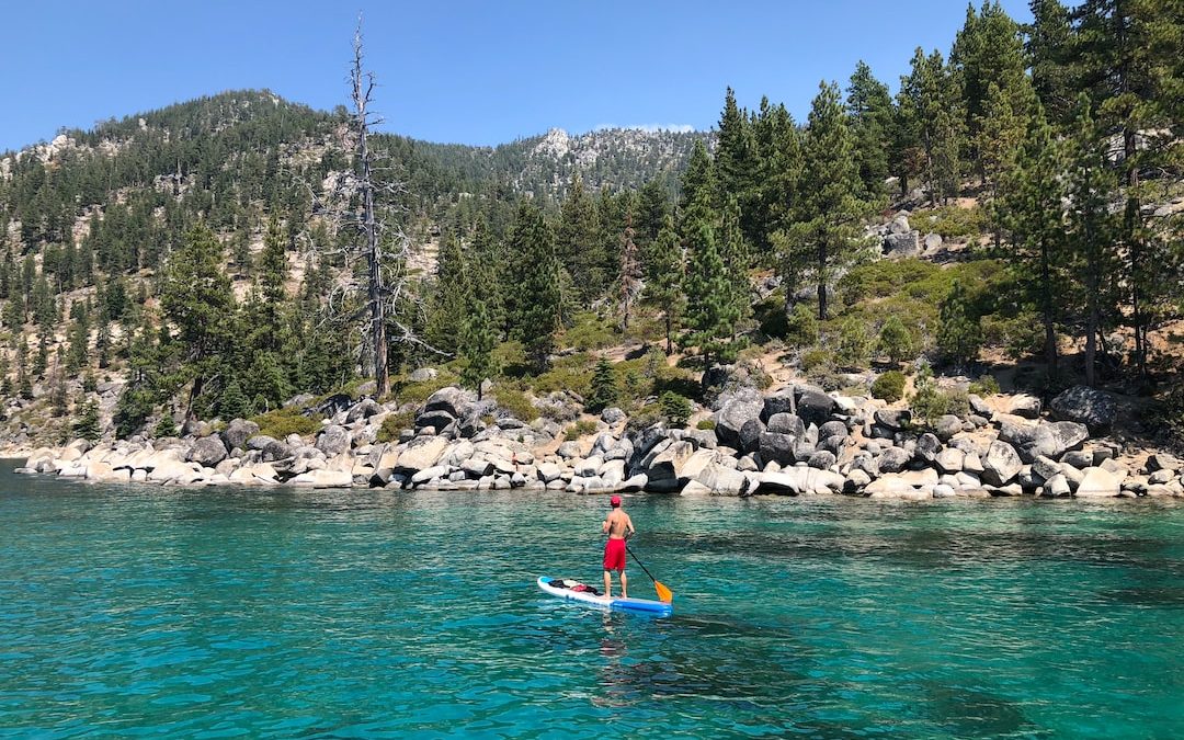 man standing on surfboard at sea during daytime