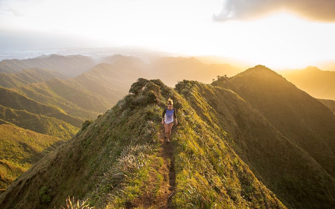 woman walking on pathway on top of hill at golden hour