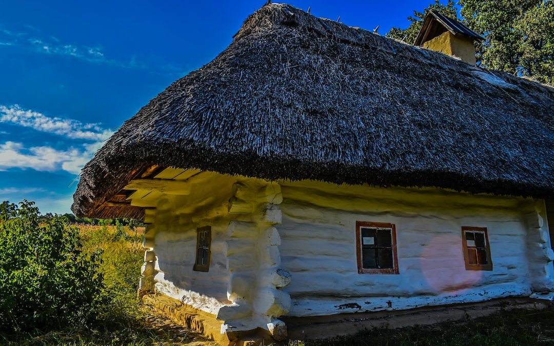 an old log house with a thatched roof