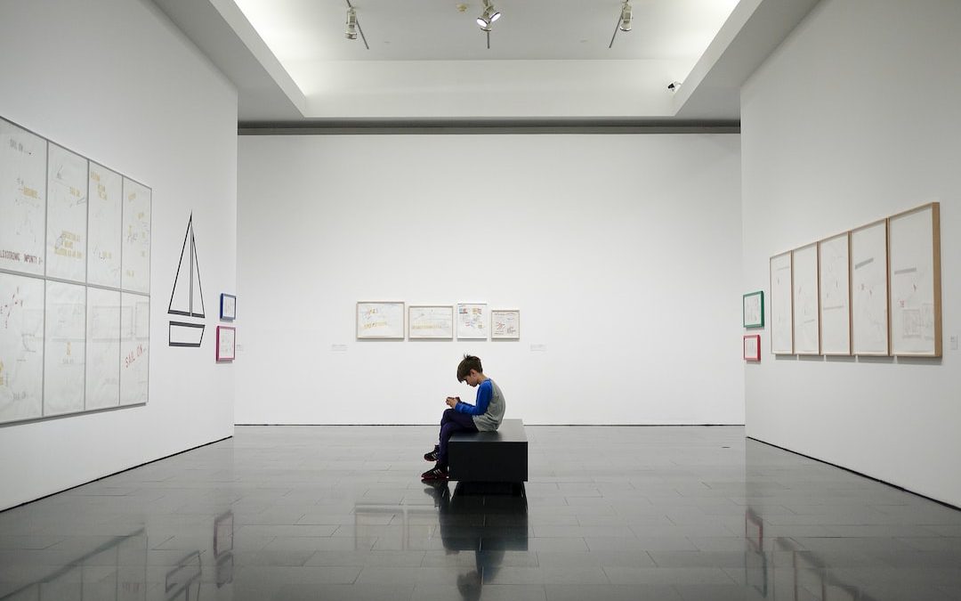 man sitting near museum painting