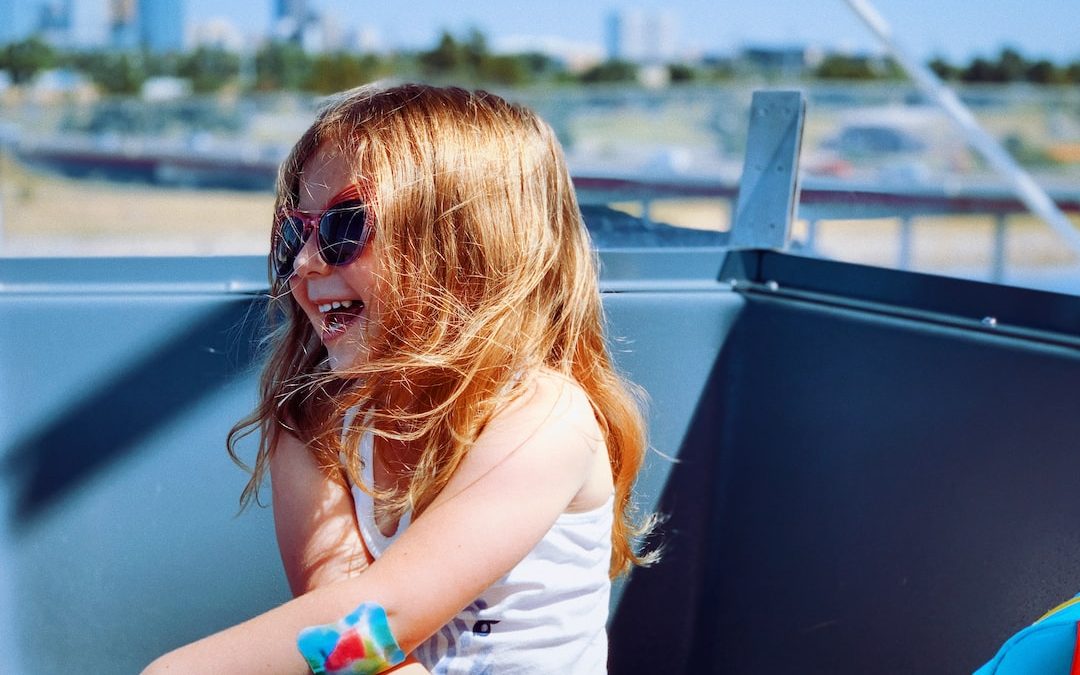 a little girl sitting on the back of a boat