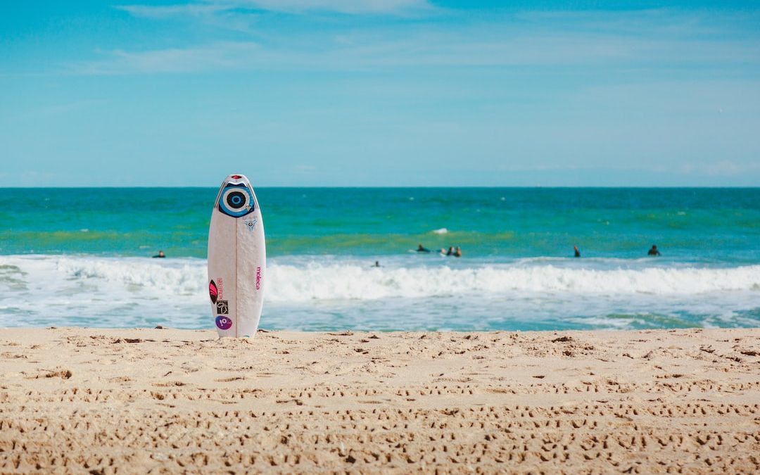 white surfboard vertically standing on seashore