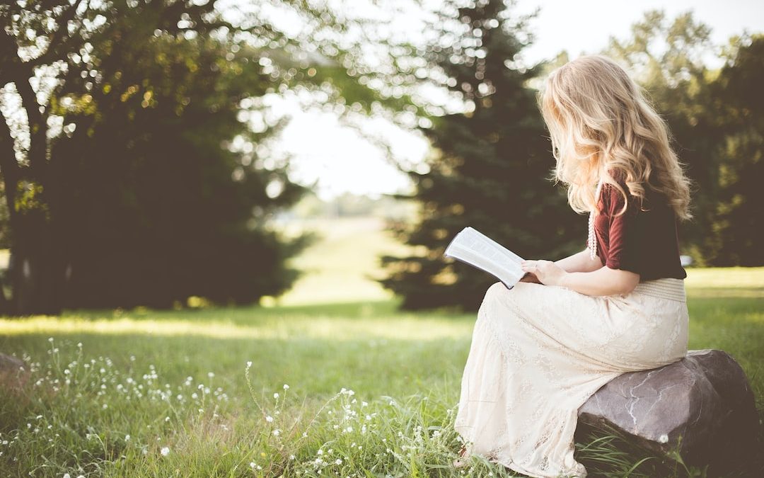 woman sitting while reading book