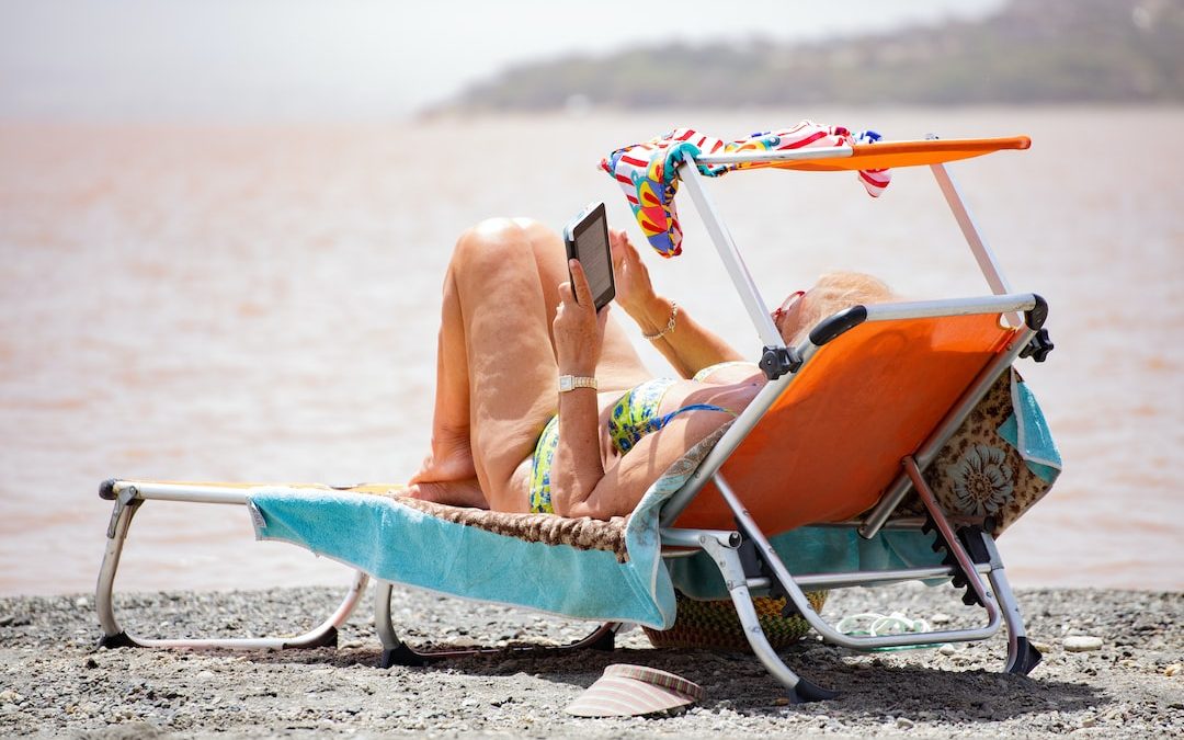 woman in white bikini lying on blue and white surfboard on beach during daytime