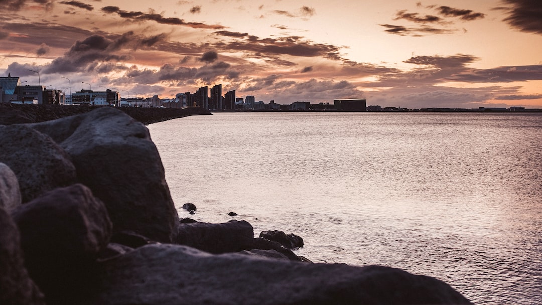 body of water near city buildings during sunset