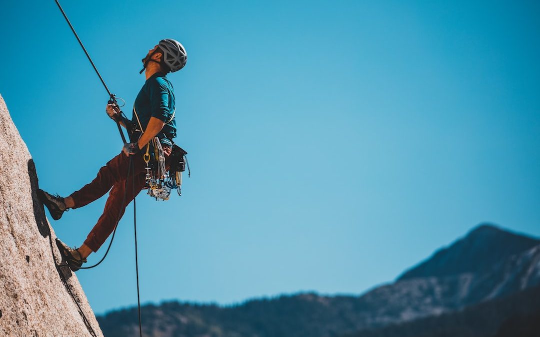 man in blue and orange jacket and black helmet riding on black and white ski lift