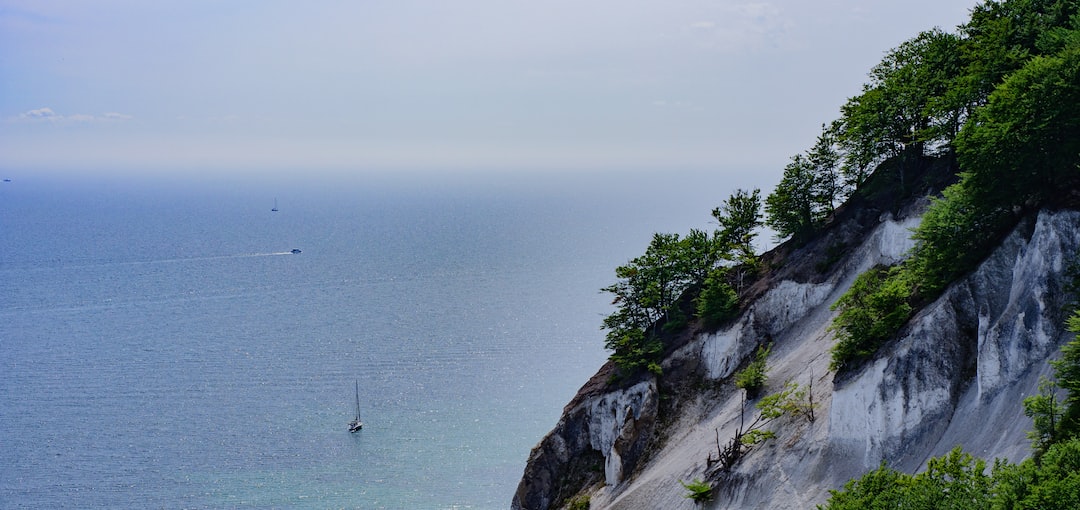 a boat is on the water near a cliff