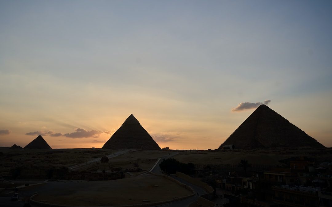 the sun is setting over the pyramids of giza